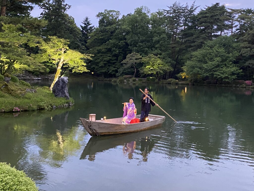 兼六園・霞ヶ池に浮かべた小舟の上で横笛を演奏する女性